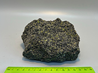 a dark basalt rock with lots of bubbles and small green peridot crystal